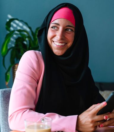 A refugee smiling while using her phone at home